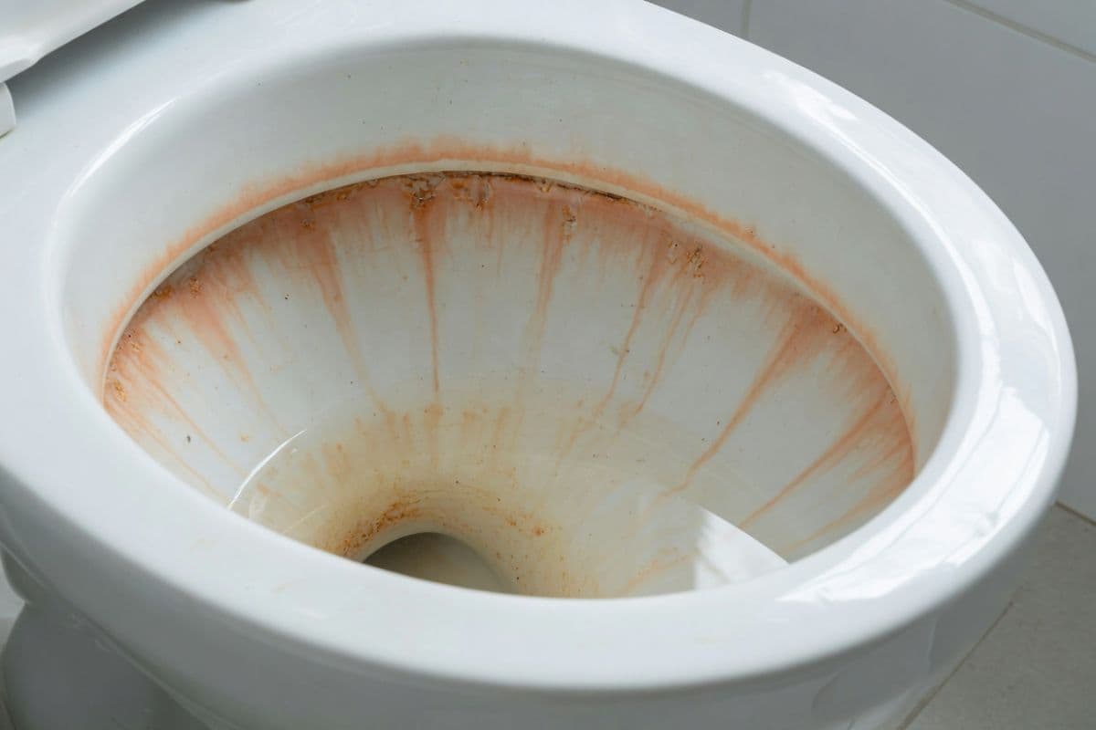 Orange iron staining visible on white porcelain bathroom fixtures caused by iron in well water