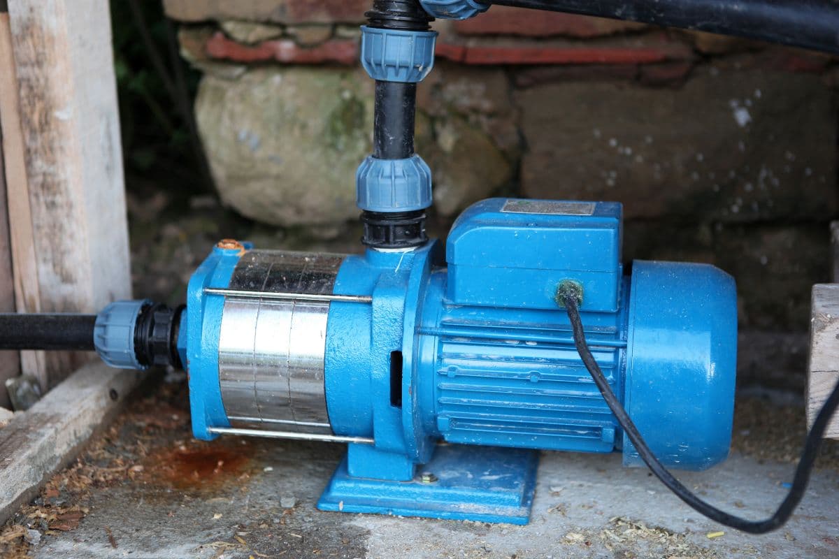 Blue shallow well jet pump installed with plumbing fittings and electrical connections